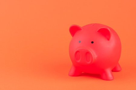 A pink ceramic piggy bank isolated on the orange backgroundの写真素材