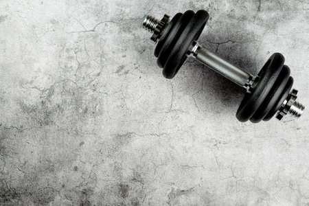 A closeup of a dumbbell on a gray surface