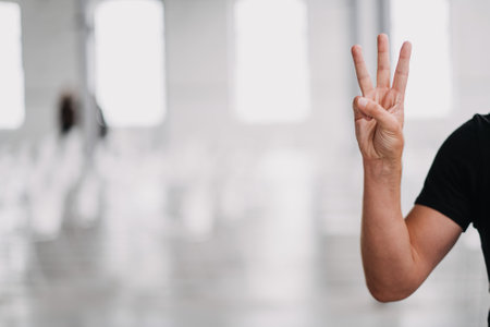 A selective focus shot of a person holding up three fingers