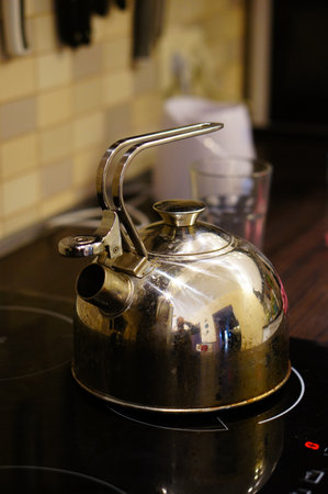A metal kettle placed on the stoveの写真素材