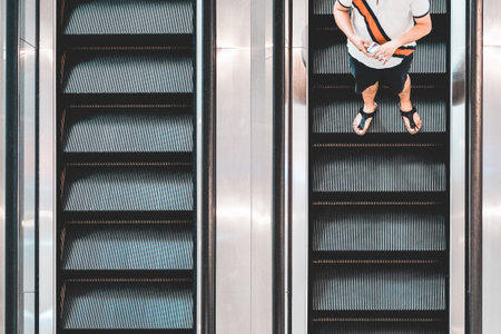A top view shot of a man with a smartphone on an escalator going downの写真素材