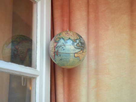 An earth globe hanging near the window and curtainの写真素材