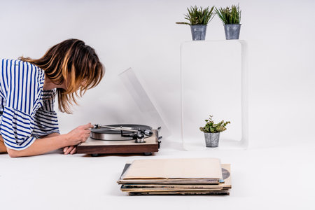 A sexy Caucasian woman turning on vinyl on a white background