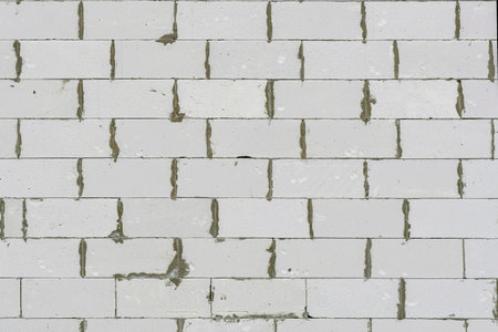 The textured surface of a stone wall of a house made of light gypsum-concrete blocks.