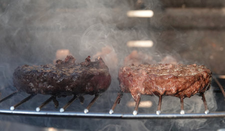 A closeup of delicious Hamburgers on the BBQ getting cooked on the grill