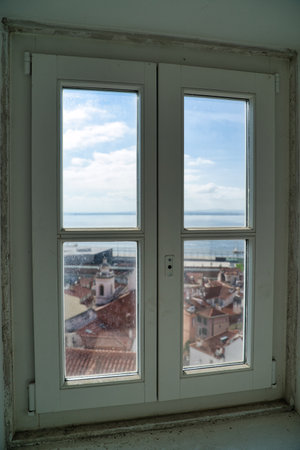 A vertical shot of a window with the view of Lisboa, Spain during daylightの写真素材