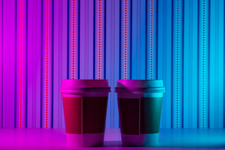 Two plastic coffee cups on a colorful backgroundの写真素材
