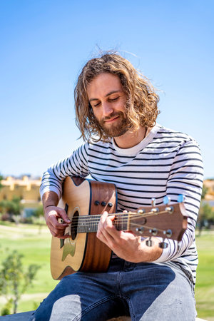 A Caucasian musician playing guitar in Spain