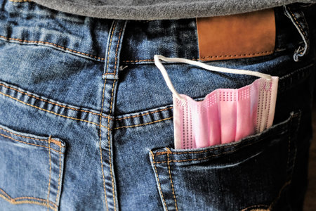 A pink face mask in the back pocket of jeansの写真素材