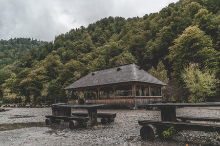 An old abandoned wooden alcove and tables in the forest mountains on a gloomy dayの写真素材