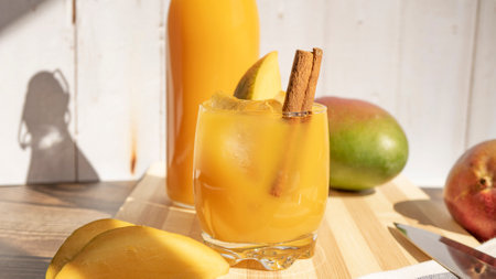 A closeup of a refreshing mango drink with a cinnamon stick, on a wooden surfaceの写真素材