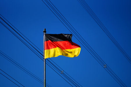 German flag in front of high-voltage power lines. Sunny contrast against a sunny blue sky. German energy supply.の写真素材