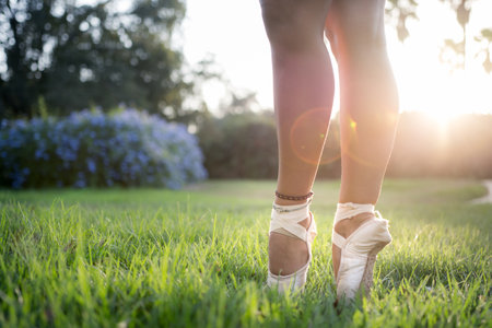 A shallow focus shot of the feet of a ballet dancer standing on the green grassの写真素材