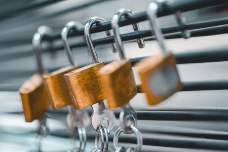 A closeup shot of padlocks with keys hanging on a blurred backgroundの写真素材