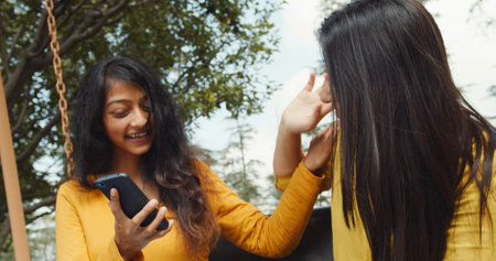 Cheerful Indian girls are scrolling on the smartphone and having funの写真素材