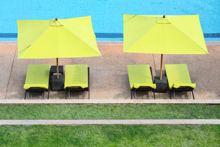 A shot of four yellow beach beds with the same color canopies near the poolの写真素材