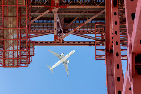 A low angle shot of a flying airplane above a metallic construction