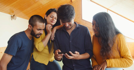 Two beautiful young Indian couples looking at the phone and discussing somethingの写真素材