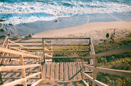 A wooden staircase of a deck on the beach surrounded by the sea on a sunny dyの写真素材