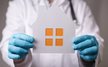 A home of paper held by hands with medical gloves. Coronavirus quarantine concept. Working from homeの写真素材