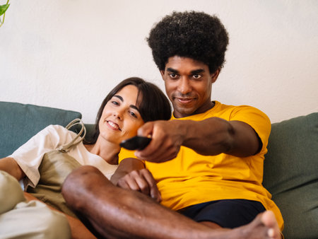 A black guy and a white Caucasian girl watching TV togetherの写真素材