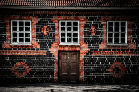 The wooden entrance door to a brick tiled house with light mortar and three old damaged glass...