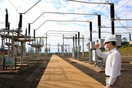 A professional man in a white hardhat inspecting inside an electrical power systemの写真素材