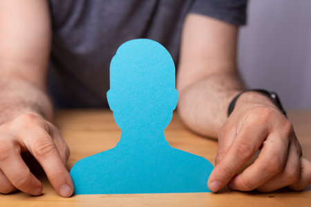 A 3d rendering of a chosen person human symbol in hand on a wooden officeの写真素材