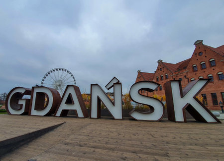 Big wheel and brick building flank the letters of Gdansk in a large signの写真素材