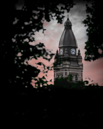 A scenic view of a clock tower with the silhouette of trees foregroundの写真素材