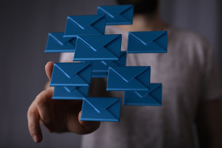A 3D rendering of colorful email inbox icons floating on a businessman's handの写真素材
