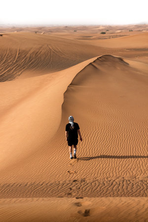 A vertical shot of a tourist leaving foot prints on the desertの写真素材