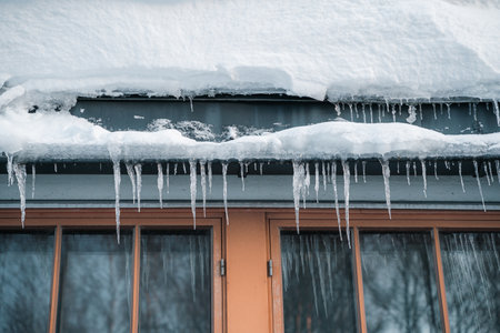 The icicles hanging in front of a house window during winter