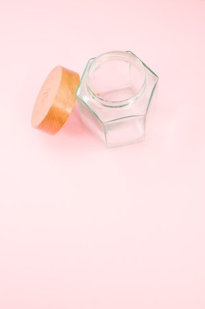 An empty glass jar with a wooden lid isolated on a pink background with copy spaceの写真素材