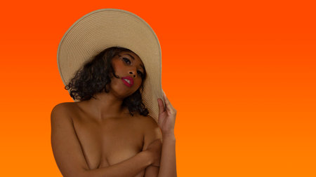 A portrait of a young sexy African American female wearing a hat and covering her breasts with a handの写真素材
