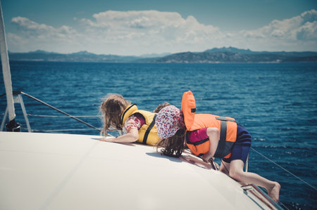 A beautiful shot of children in life vests climbing on a boatの写真素材