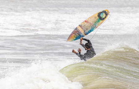 The surfer with the board jumping over the wave.