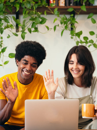 A vertical shot of a black guy and a white Caucasian girl greeting during a video callの写真素材