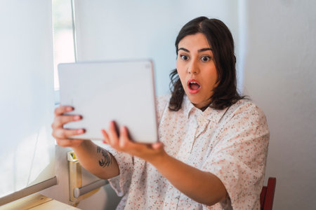 A shallow focus of a surprised Spanish girl using a tablet indoors