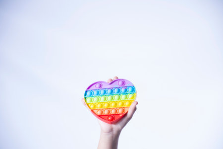 A closeup shot of a female holding a rainbow-colored pop-it toy isolated on a white backgroundの写真素材