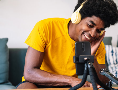 A black man with curly hair video calling with his friends on the phoneの写真素材