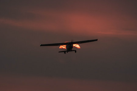 An aircraft at flight against a setting sun behind the cloudsの写真素材