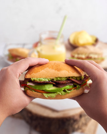 Male hands holding a roast beef sandwich on a blurred backgroundの写真素材