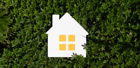 A 3d rendering of an implied flat lay design with a miniature white toy house on green grassの写真素材