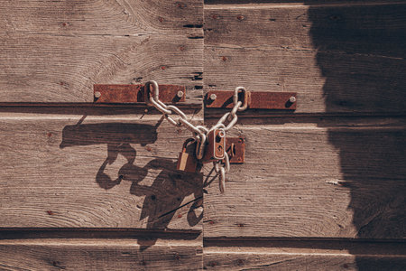 the old rusty padlock securing old wooden doorの写真素材