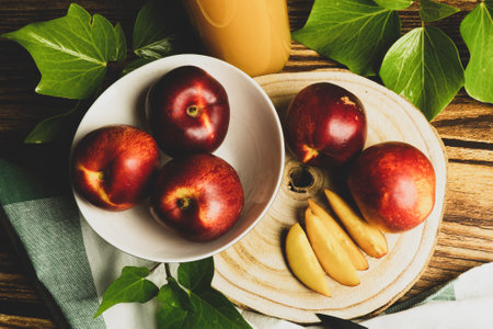 A top view of peaches whole and sliced on a wooden surface, surrounded by leavesの写真素材