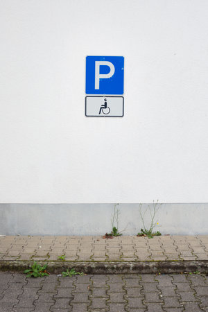 A vertical shot of the parking and the wheelchair road signs on a wall outdoorsの写真素材