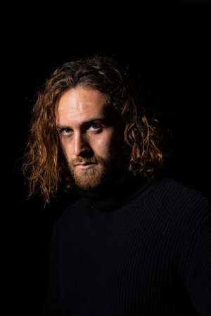 A sexy Caucasian man with long hair on a black background