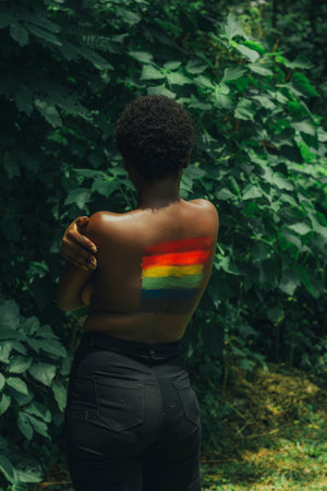 An LGBT flag painted on the back of a black shirtless femaleの写真素材