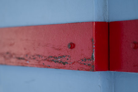 Close-up of bolt emerging from the building wall painted in ed and blue. Selective focus, perfect...